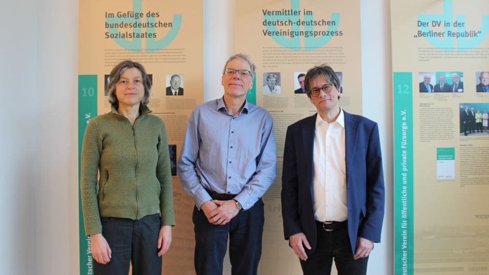 Foto von Frau Kaps, Herrn Krampe und Herrn Prof. Dr. Coullery vor der historischen Ausstellung des Deutschen Vereins in der Geschäftsstelle des Deutschen Vereins