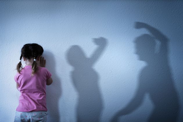 Bild: Traugiges Kind im Vordergrund, im Hintergrund Schatten von einer Frau und eines Mannes, der den Arm hebt, © istock.com /AndreyPopov