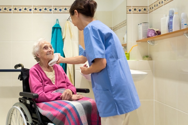 Bild: Pflegerin, die eine Senioren im Rollstuhl wäscht