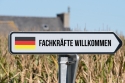 Foto: Schild mit Deutschlandflagge und Aufschrift: Fachkräfte willkommen