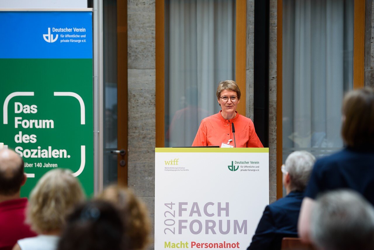 Foto von Nora Schmidt am Rednerpult. Im Hintergrund ein Banner des Deutschen Vereins. –