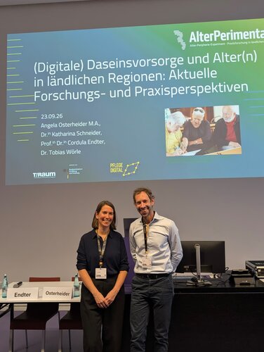 Foto zeigt Dr. Anna Richter und Dr. Tobias Wörle bei einem gemeinsamen Vortrag zum Thema "Digital gestützte Daseinsvorsorge. Neue Spielräume für Kommunen und ambulante Pflege in ländlichen Räumen?"