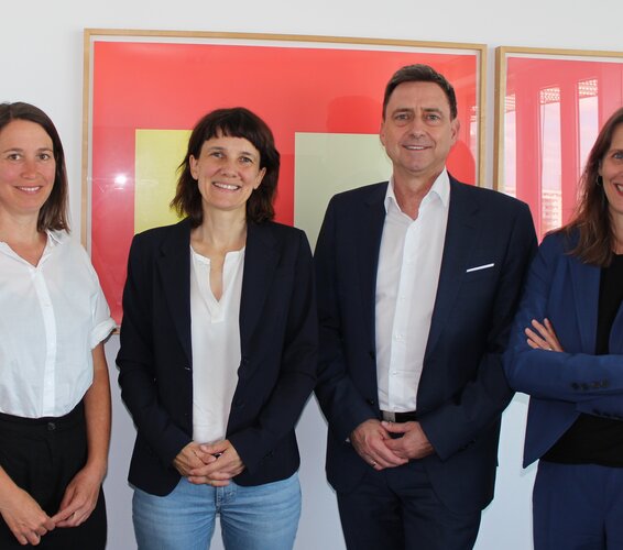 Foto mit roten Bildern im Hintergrund. Das Foto zeigt Dr. Anna Richter (DV), Dr. Antje Schwinger (GKV), Oliver Blatt (GKV) und Dr. Verena Staats (DV)