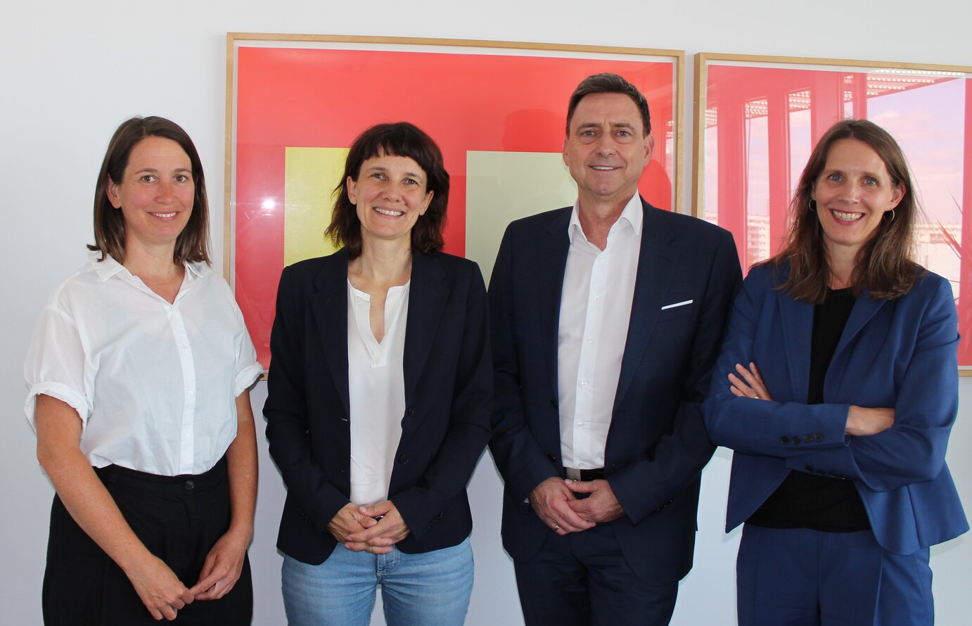 Foto mit roten Bildern im Hintergrund. Das Foto zeigt Dr. Anna Richter (DV), Dr. Antje Schwinger (GKV), Oliver Blatt (GKV) und Dr. Verena Staats (DV)
