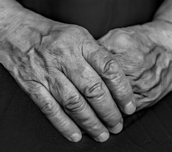 Foto in schwarz-weiß von zwei Händen eines Senioren oder einer Seniorin. – 