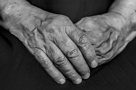 Foto in schwarz-weiß von zwei Händen eines Senioren oder einer Seniorin. – 