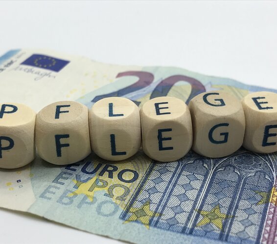 Zu sehen ist ein 20-Euro-Schein auf dem mit einzelnen Buchstaben-Würfeln das Wort "Pflege" gebildet wird. – 