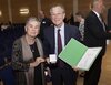 Eine Frau und ein Mann halten eine Urkunde und eine Plakette